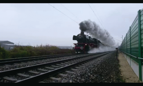 a train on the railroad tracks with smoke coming from it
