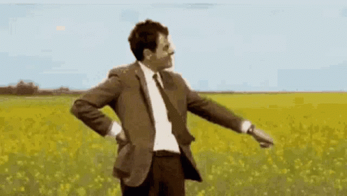 the man in a suit is holding his hands out while standing in a field