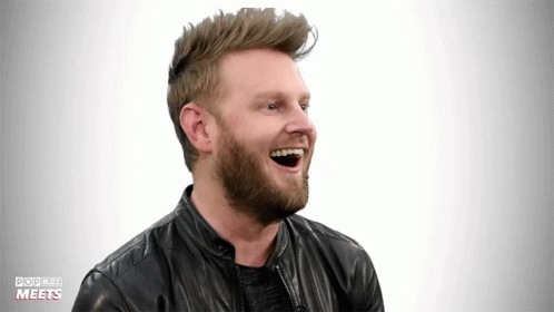 a man with a beard laughing while wearing a black leather jacket