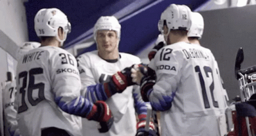 three guys in white hockey uniforms are standing