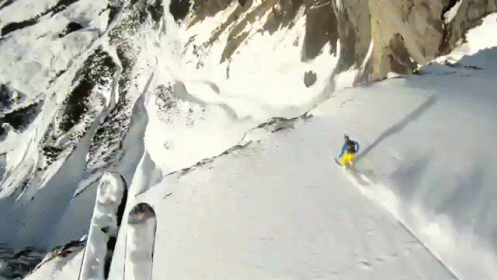 snow boarder on ski slope surrounded by rocks and a mountain