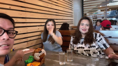 three women sit at a table smiling while eating