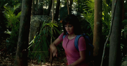 a woman with a backpack is walking through a jungle