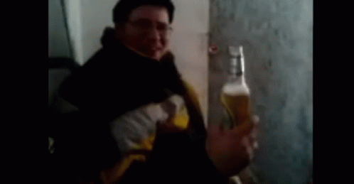man drinking beer from blue bottle in corner of room