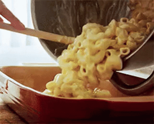 a container with macaroni and cheese being stirred with a plastic spatula