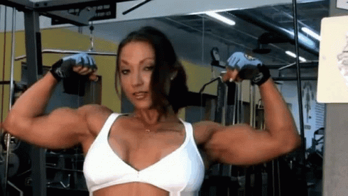 a female bodybuyer poses for the camera in a gym