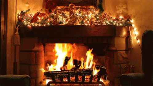 fireplace with fire lit up at night and decorations