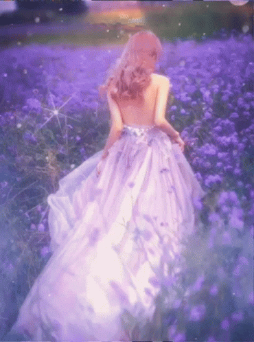 a beautiful young lady in a gown walking through some flowers