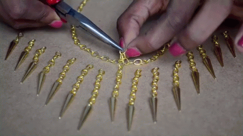 the hands of a woman are creating a chain with beads