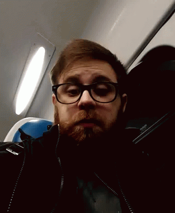a man wearing glasses, and sitting on an airplane