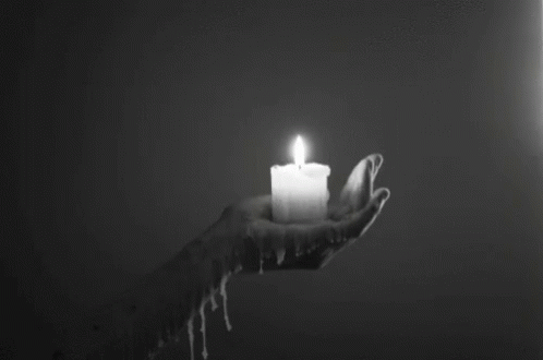 a white candle sitting on top of a hand