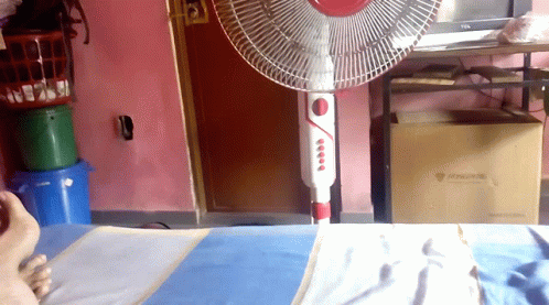 a white fan that is sitting on a bed
