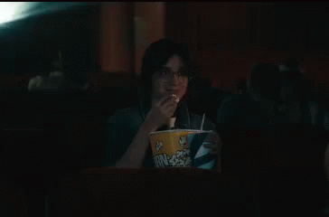 a woman sitting in a restaurant at a table with popcorn