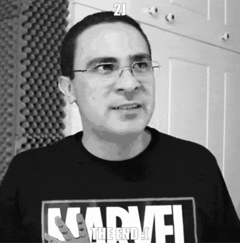 a man wearing glasses standing in front of a door