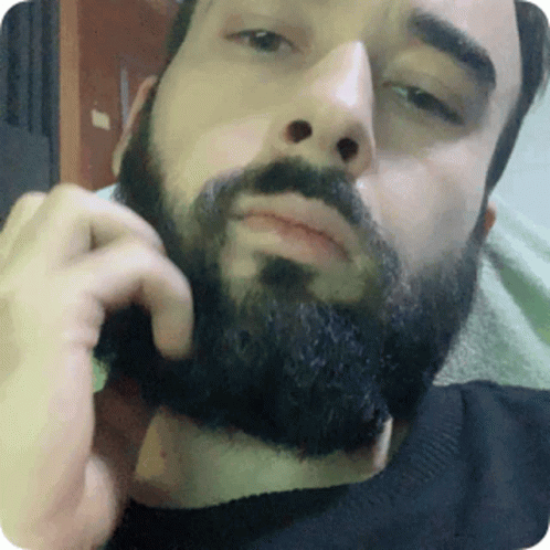 a bearded man is talking on a cellphone