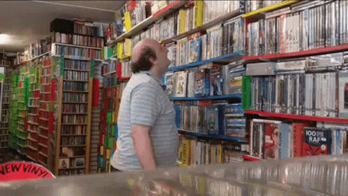 the person is looking at the dvd shelves in the store