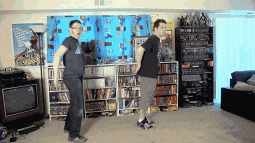 two men playing with nintendo wii and some shelves