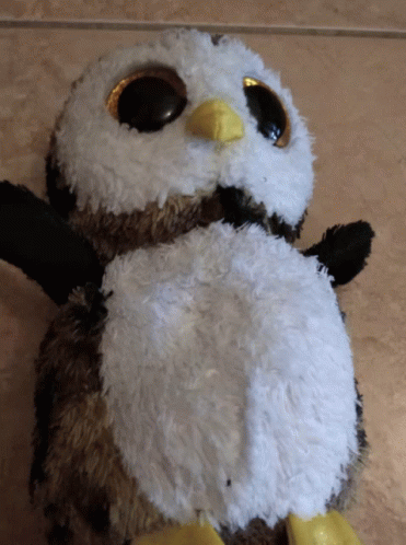 a stuffed toy penguin with big eyes standing on the ground