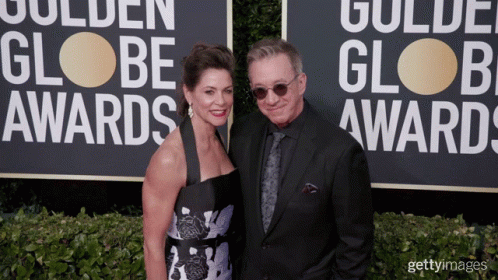 a man and woman posing for a po next to a sign that reads golden globe awards