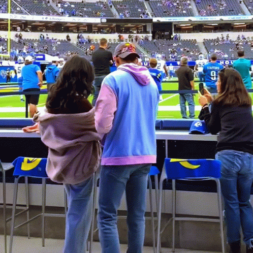 a man and woman standing in the sidelines of a stadium