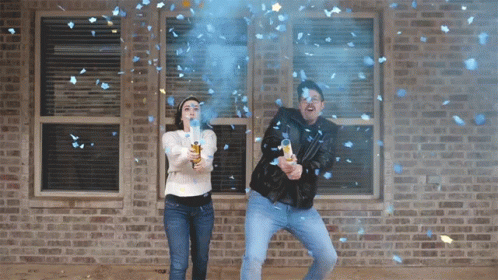two people standing in front of a brick building with confetti