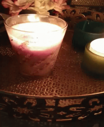 a candle sitting on top of a tray near flowers