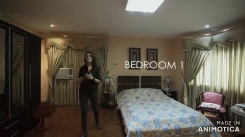 a woman that is in a bedroom by a bed