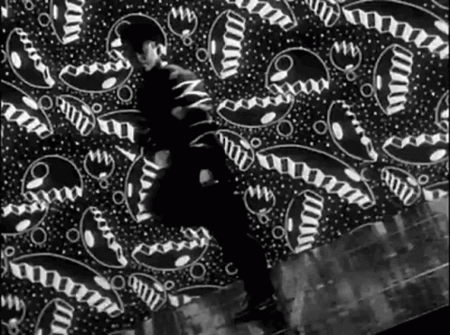 a man standing against a wall with black and white abstract art on it
