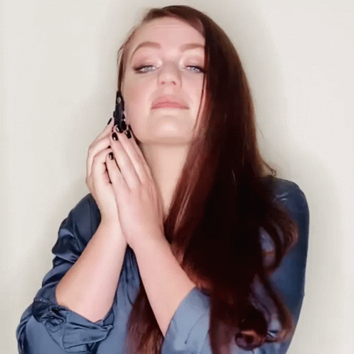 the woman is touching her hair with one hand