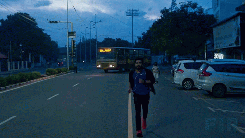 a man crosses the street in front of a bus