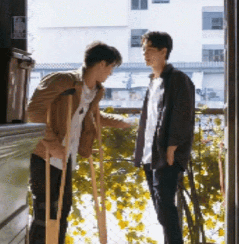 two boys are standing outside of the window of their building