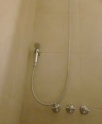 a shower head next to several faucets in the shower
