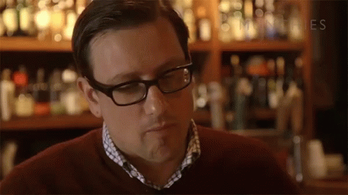 a man in glasses stands in a bar