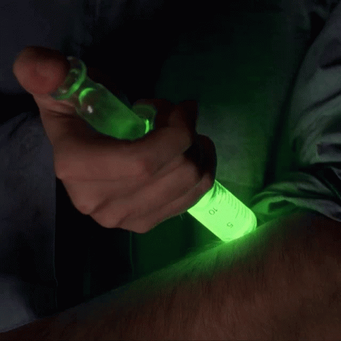 a green lighter being refilled in a dark room