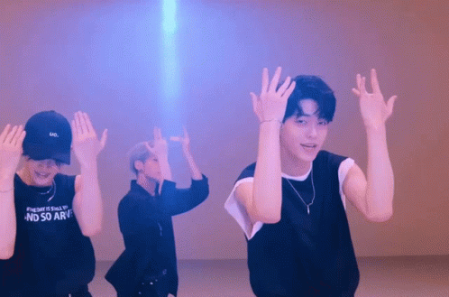 three male s are performing dance moves with their hands in the air