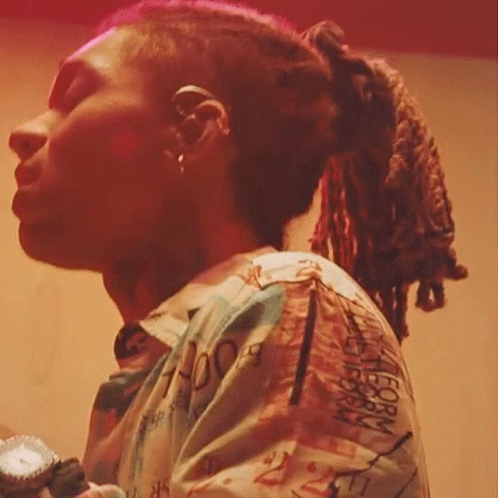 a woman with dreadlocks is holding a microphone and wearing an ice cream container