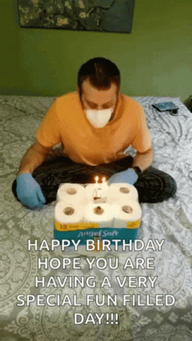 a man in blue is sitting on a bed and reading a birthday card