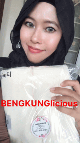 an asian woman wearing a hijab is holding a package