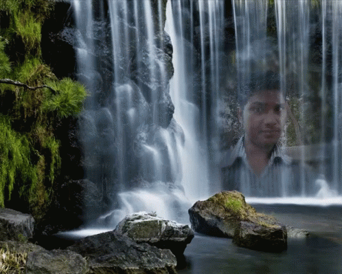 a man looking into a waterfall that is near water