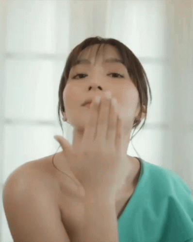 an asian woman covers her mouth with both hands