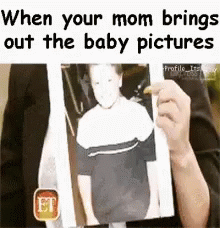 a person holding a white poster with a text that reads, when your mom brings out the baby pictures