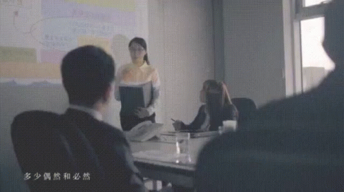 a lady stands at a conference table with other people