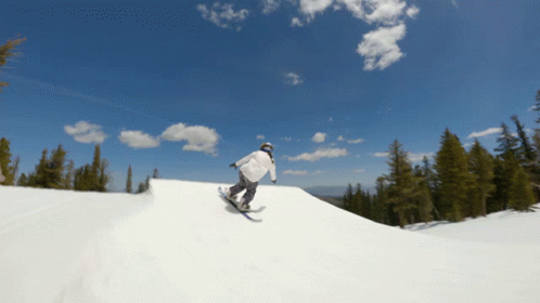 a man riding a snowboard down the side of a snow covered hill