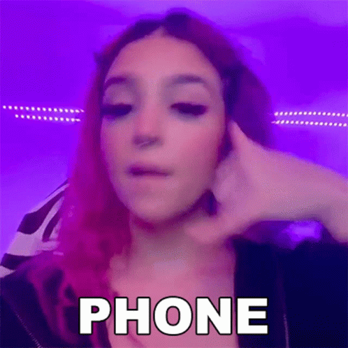 a person with purple hair and blue makeup, looking at a cellphone