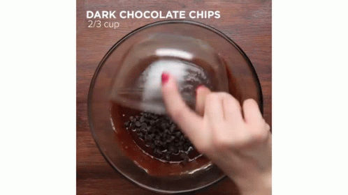 there is a hand reaching for a chocolate in the bowl