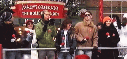 several people standing behind a sign with the message macy's celetion the holiday season