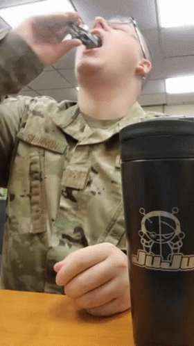 an air force officer eating soing out of a cup