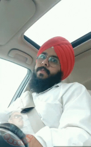 man in a turban drives a car, while wearing sunglasses and a watch