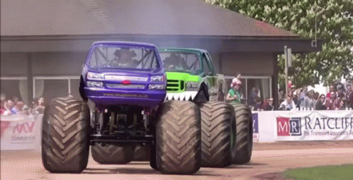 the red truck is pulling the green monster truck
