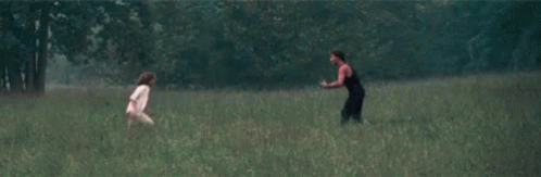 a woman running in a field holding a frisbee